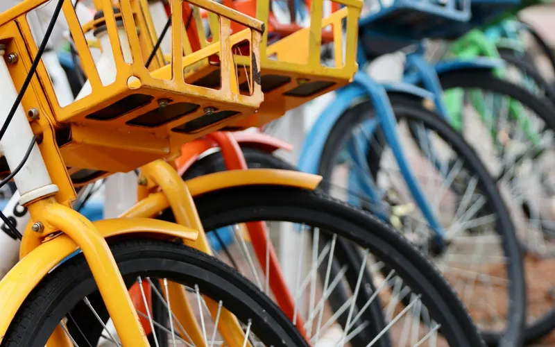 A row of colourful rental bikes with baskets