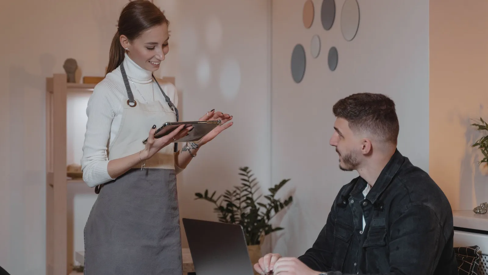 Serveerster met een tablet helpt een gast aan tafel