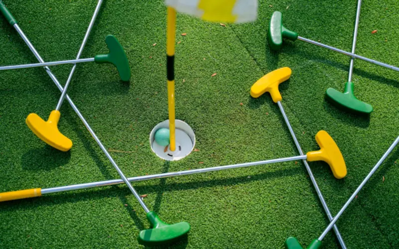 Putters around the hole on a mini golf course, with the ball in the cup