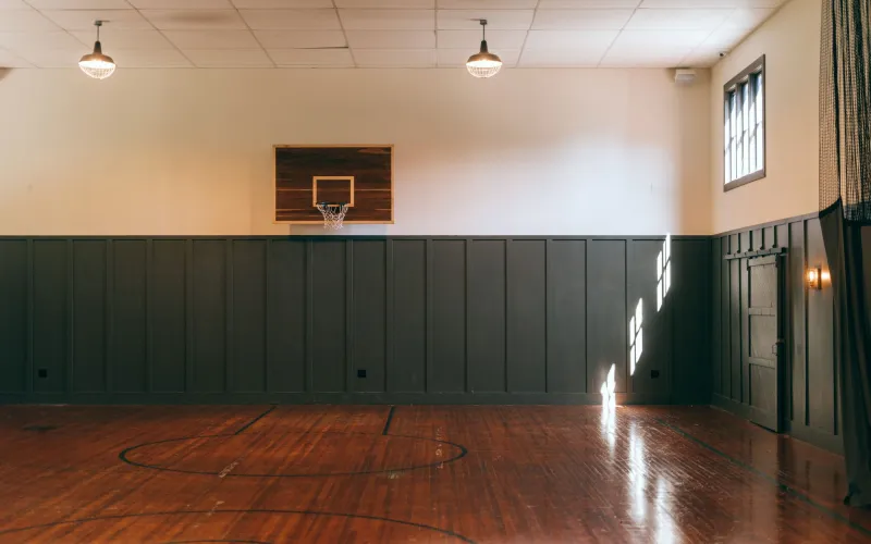 Eine leere Sporthalle mit Holzboden und einem Basketballkorb