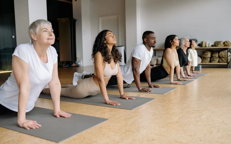 Eine Gruppe in der Kobra auf Yogamatten in einem hellen Studio